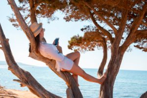 Girl with smartphone on a tree at the beach Girl with smartphone on a tree at the beach